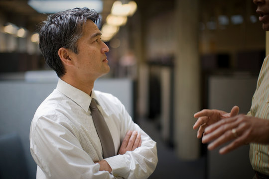 Mature adult businessman talking with a male colleague in an office.