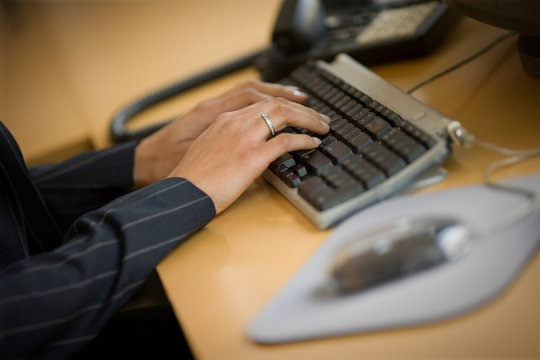 Computer keyboard being used by a business woman in an office.
