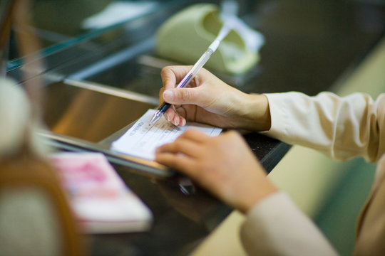 Women's hands writing in a check book.