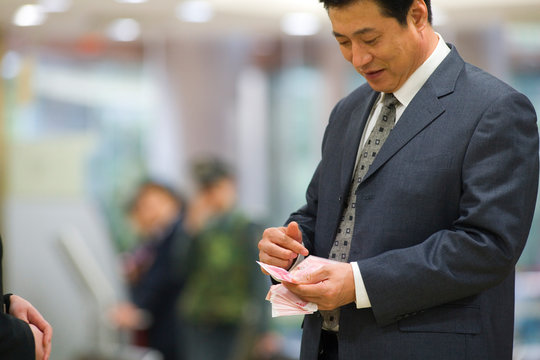 Businessman counting a stack of dollar bills.