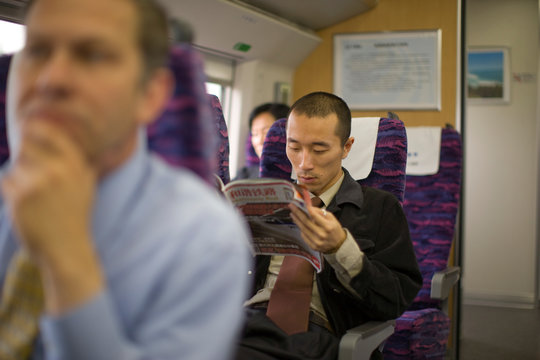 Young adult businessman sitting on a train.