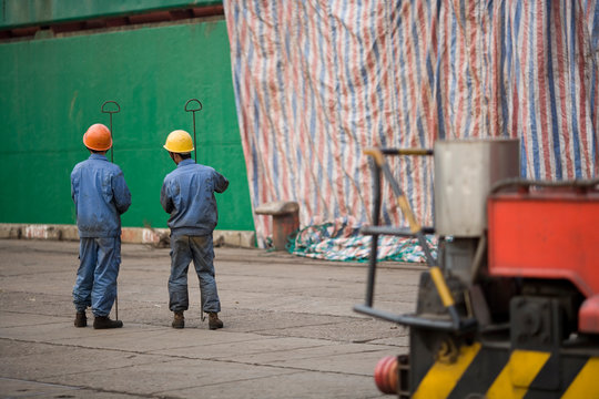 Two male construction workers standing in a shipping yard.