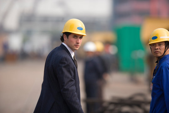 Portrait of a businessman and a construction worker wearing hardhats.