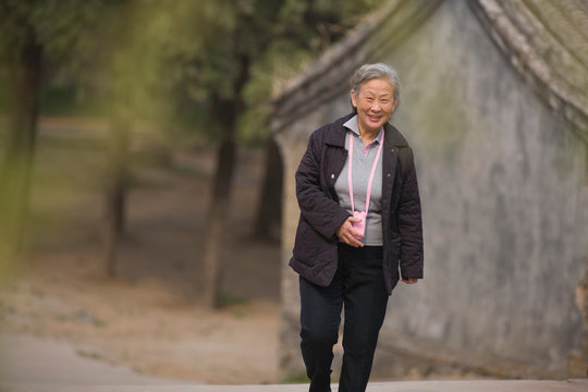 Portrait of a senior woman walking along a road.