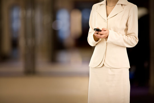 Cellphone being used by a young adult business woman in an office.