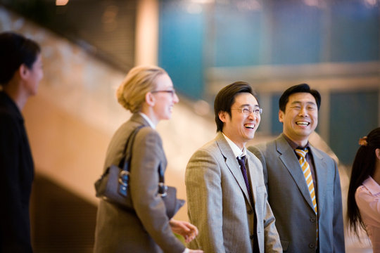 Young adult businessman laughing with colleagues in a building.