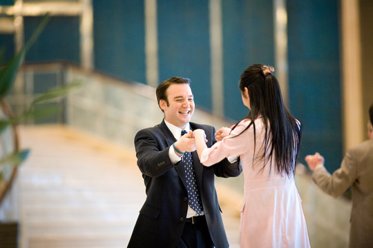 Young adult couple dancing in a hotel lobby.