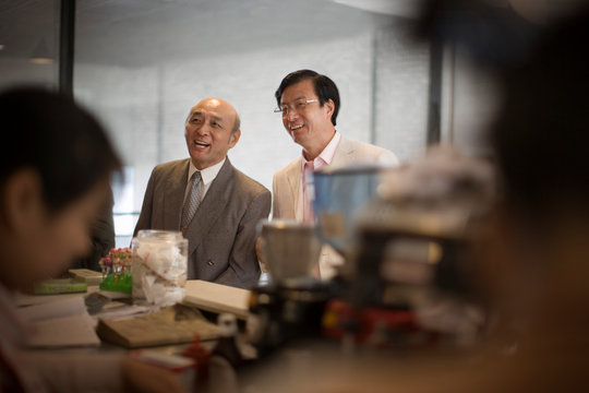 Senior adult man standing with a mid-adult man at a shop.