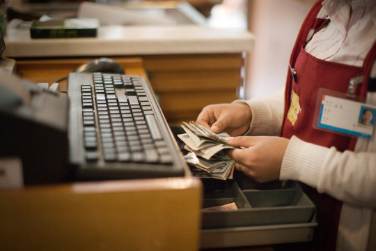 Money being placed into a till of a register.