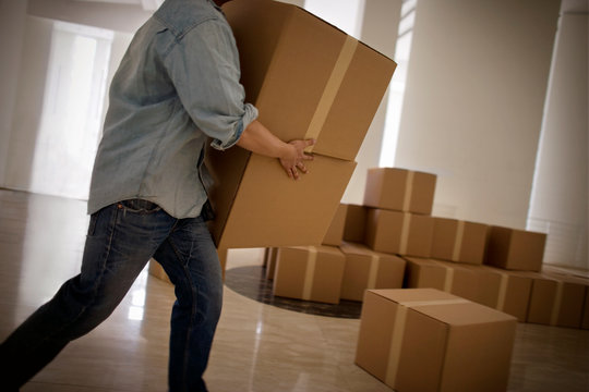 Young adult man carrying boxes in a building.