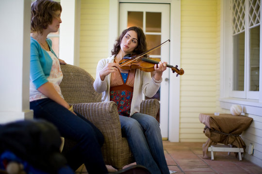 Young woman playing the violin for her friend
