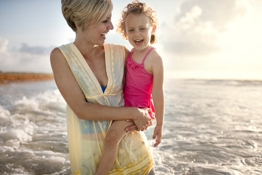Smiling mother and daughter enjoying beach
