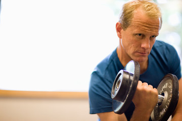 Mid-adult man lifting weights in a gym.