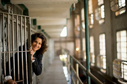 Portrait of a smiling business woman exiting a cell in a derelict building.
