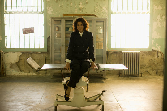 Portrait of a mid-adult business woman sitting on a table on an old operating room.