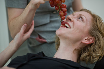 Women lying on floor of house eating grapes