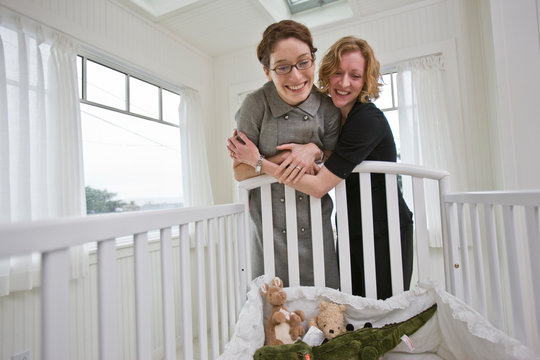 Women standing over bassinet in house