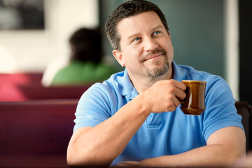 Thoughtful mid adult man enjoying a cup of coffee at a diner.