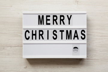 'Merry Christmas' words on lightbox over white wooden background, overhead view. Flat lay, from above, top view.