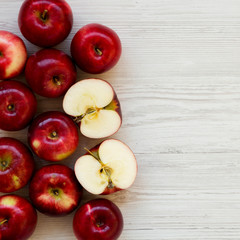 Raw red apples on white wooden background, overhead view. Flat lay, from above, top view. Copy space.