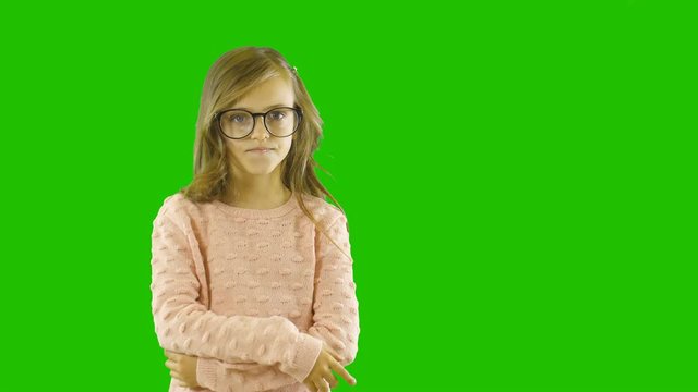 A little playful girl with curly hair in big glasses is positively surprised and shows her finger to the side showing off something, destkay fashion shooting, shooting on an isolated background