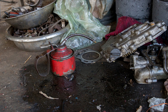 Vintage Red Lubricant Oil Can With Greasy Tools On Dirty Concrete Ground - Repairing Eqipment