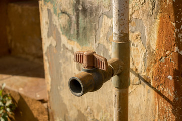 Vintage Dirty Plastic Water Faucet with PVC Valve - Old Concrete Texture - Sunny Warm Day in Home Garden