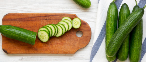 Fresh raw green cucumbers, top view. Flat lay, from above, overhead. White wooden surface.