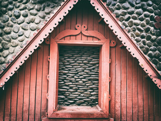 Part of the front wall of a wooden house on a gray cobblestones