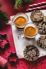 Christmas chocolate cookies with sesame and New Year's festive decorations on the table and two cups of espresso coffee