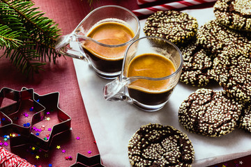 Christmas chocolate cookies with sesame and New Year's festive decorations on the table and two cups of espresso coffee
