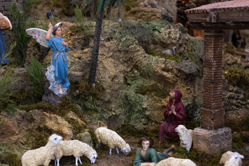 Nativity set with Joseph looking up at Saint Mary standing while shepherd resting and sheep eating...