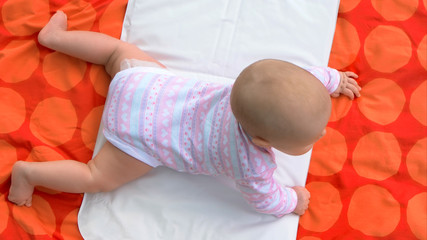 Beautiful caucasian baby girl on blanket. Sweet tiny baby girl is lying on stomach. Tips for parents.