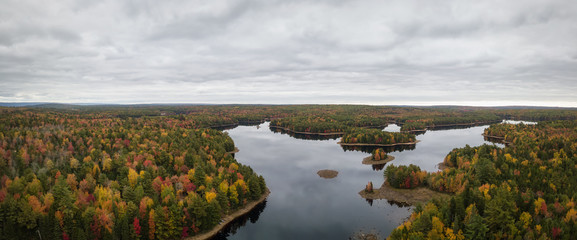 Aerial panoramir view of a beautiful lake in the forest with colorful trees during fall season. Taken in Grand Lake Flowage, Nova Scotia, Canada.