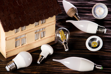 Led lamps lie near the house layout on wooden background 