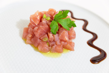 A delicious tartare of fresh Mediterranean tuna. Seasoned with extra virgin olive oil and parsley The dish is decorated with parsley and balsamic vinegar of Modena.