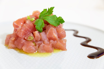 A delicious tartare of fresh Mediterranean tuna. Seasoned with extra virgin olive oil and parsley The dish is decorated with parsley and balsamic vinegar of Modena.