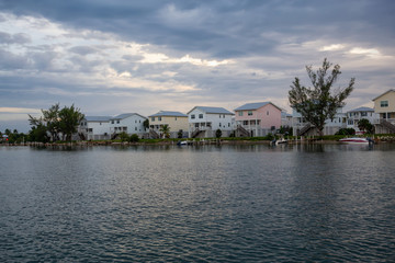 Obraz premium View of residential homes on the ocean shore during a vibrant cloudy sunset. Taken in Key West, Florida Keys, United States.