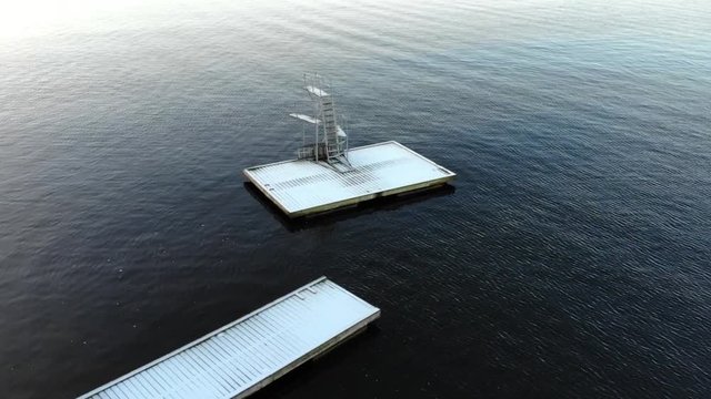 Drone view of a diving platforme on a pontoon on a lake covered with snow in Sweden