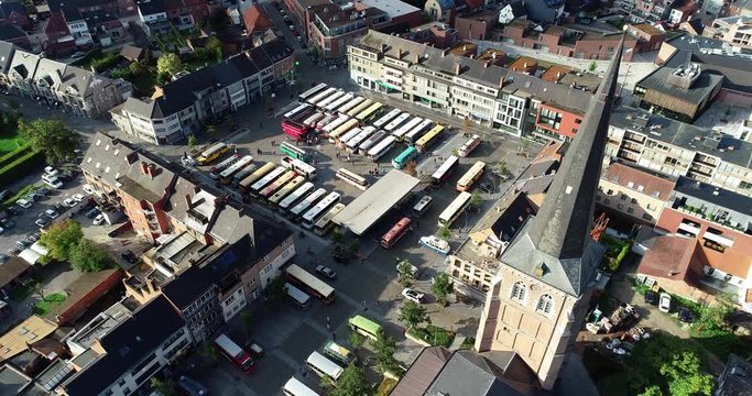 An aerial shot of busses gathering on a town square with the church dominating the view.