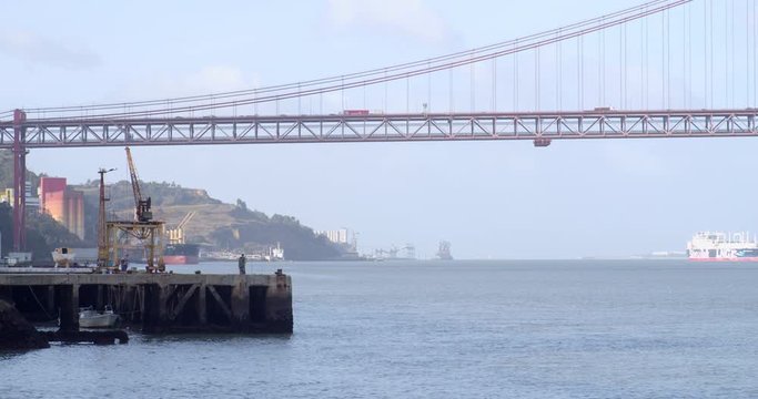 Fisherman at Almada's sea break with Lisbon Bridge at the end of the frame. Shot in Almada, Portugal