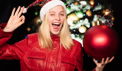 Woman on christmas. Happy advertising. Cheerful girl and OK gesture. A huge toy on a Christmas tree. Successful preparation for holidays. Poster about sale.