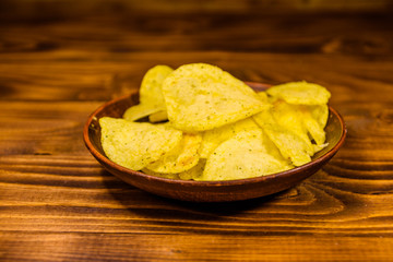 Ceramic plate with potato chips on wooden table