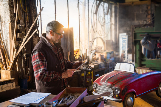 A man in his DIY workshop to repair an old pedal car