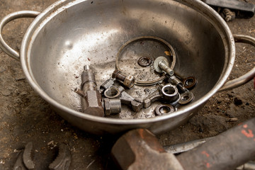 Oily Nuts and Bolts in Old Metal Pan - Dirty Tools on Concrete Ground
