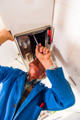 Obraz premium Handyman repair vent hood with screwdriver