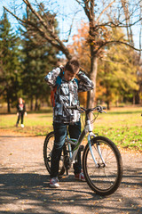 Fototapeta na wymiar Young happy boy standing with his bike in nature,enjoying the sunny weather.