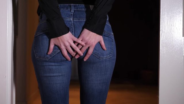 Woman walks and immediately stops because of stabbing anal pain, she puts hands on her buttocks
