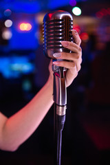 Stand and microphone.Hand holding vintage microphone