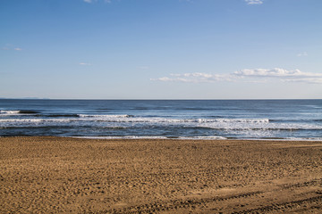 sea coast view with waves, sand beach and blue sky